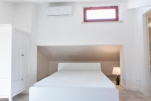 um quarto com uma cama branca e uma janela em S271 - Sirolo, deliziosa mansarda condizionata arredata con gusto em Sirolo