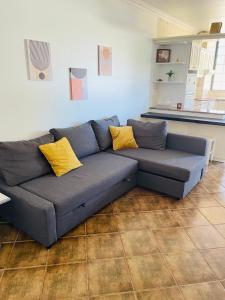 Sofá azul en la sala de estar con almohadas amarillas en Apartamento Praia do Vau, en Alvor