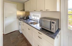 a kitchen with a microwave and a sink at Beautiful Caravan In Tzummarum With Wifi, 2 Bedrooms And Swimming Pool in Tzummarum