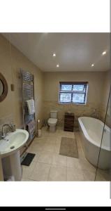 a bathroom with a tub and a sink and a toilet at Sunset cottage in Burry Port