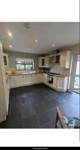 a large kitchen with white cabinets and a tile floor at Sunset cottage in Burry Port