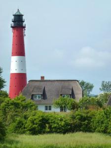 un phare rouge et blanc assis au-dessus d'une maison dans l'établissement Austernfischer Haus, à Pellworm