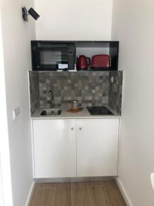 a small kitchen with a sink and a microwave at Casa dos Bernardos in Trancoso