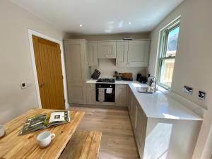 a kitchen with white cabinets and a wooden table at Luxurious Beach House Chesil Beach. Sleeps 6 in Castletown