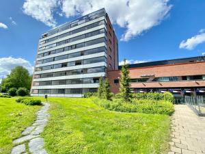 un edificio alto frente a un campo verde en Tammer Huoneistot - City Suite 3 - Public Sauna, Gym & Pool, en Tampere