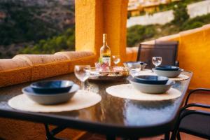 una mesa con tazones y copas y una botella de vino en Apartmán Marcella, Cumbre del Sol, en Cumbre del Sol