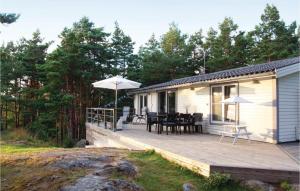 a house with a wooden deck with tables and umbrellas at Gorgeous Home In Vikbolandet With Wifi in Arkösund