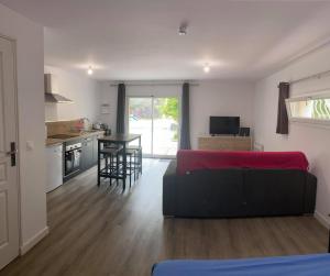 a living room with a red couch and a kitchen at Le Grenadier in Saint-Mitre-les-Remparts