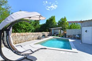 basen z huśtawką i parasolem w obiekcie House Kacana 2163 w mieście Vodnjan
