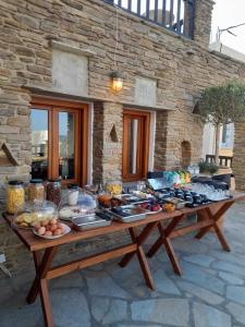 a table with food on it in front of a stone building at Spitalia Rooms in Tinos Town