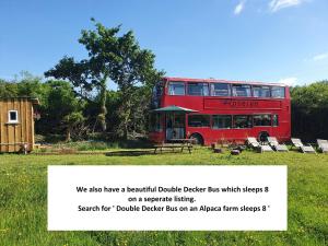 a red double decker bus parked in a field at Dartmoor Reach Alpaca Farm Heated Cabins in Bovey Tracey