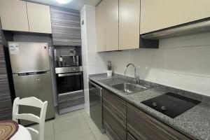 a kitchen with a sink and a stainless steel refrigerator at Hermoso departamento en la Península en Iquique in Iquique