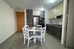 a kitchen with a white table and chairs in a room at Hermoso departamento en la Península en Iquique in Iquique +1 photo