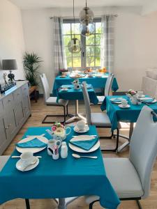 uma sala de jantar com mesas azuis e cadeiras brancas em Les Grands Bois em Pomport