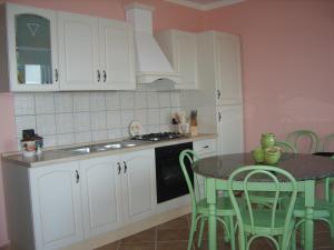 una cucina con mobili bianchi e un tavolo con sedie verdi di VISTA MARE a Budoni