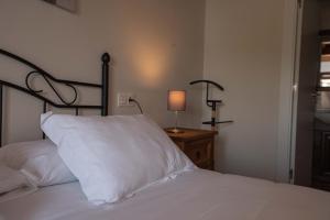 Una cama con una almohada blanca y una lámpara sobre una mesa en Apartamentos Rurales Playas De Niembro en Llanes