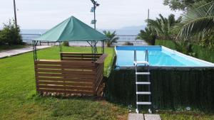 a swimming pool with a ladder and a green umbrella at Meliades Villa in Agioi Theodoroi