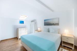 - une chambre blanche avec un lit bleu et 2 tables de chevet dans l'établissement Casa da Tita Alvor, à Alvor