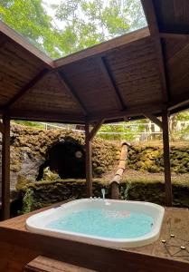 une baignoire jacuzzi sous un pavillon avec un mur en pierre dans l'établissement LN ETNA HOUSE-villa ad uso esclusivo, à Pedara