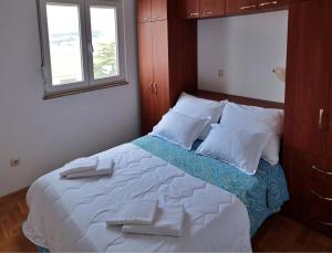 a bedroom with a bed with white sheets and pillows at Apartment Carole in Trogir
