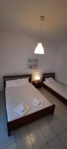 a bedroom with two beds and a light and a lamp at KANALI HOLIDAYS APARTMENT in Kanali