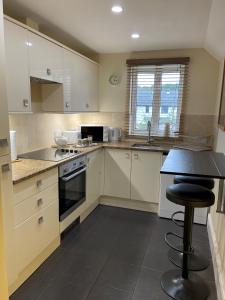 a kitchen with white cabinets and a table and a stool at Ground Floor Garden Cottage, near Stonehenge in Shrewton