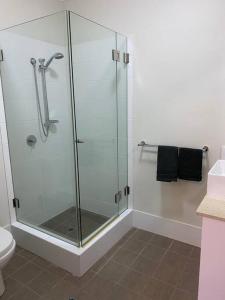 a shower stall with a glass door in a bathroom at Stylish Modern Airport City WIFI Park Netflix Wine in Perth