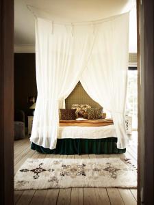 a bedroom with a canopy bed with a curtain at The Norrmans Farmhouse Boutique Hotel in Klippinge