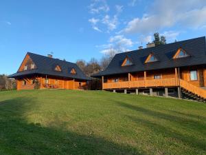 uma grande casa de madeira numa colina com um campo de relva em Bieszczadzkie Chatki - Willa Stasia em Ustrzyki Dolne