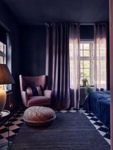 um quarto com uma cadeira, uma cama e uma janela em The Norrmans Farmhouse Boutique Hotel em Klippinge
