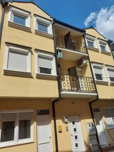 - un bâtiment jaune avec des portes blanches et un balcon dans l'établissement Apartment Toskana, à Novi Sad