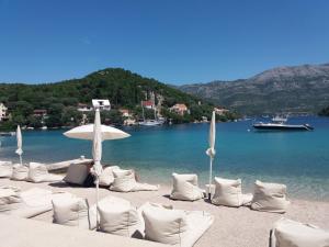 a beach with white chairs and an umbrella and water at Apartmani Luka in Korčula