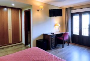 a bedroom with a desk and a bed with a pink bedspread at Hostal Plaza Mayor in Torrejón de Ardoz +12 photos