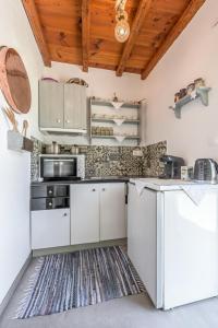 a kitchen with white appliances and a wooden ceiling at Ralaki Cottage in Ralaki