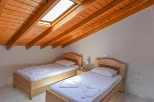 two beds in a room with wooden ceilings at DEJA BLUE Maisonette in Kokkari