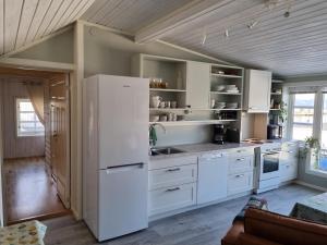 a kitchen with white cabinets and a large refrigerator at Loftsleilighet midt i sentrum in Skjervøy
