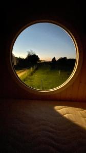 Una ventana redonda en una habitación con vistas al campo en Glamping MARINGOTKA - malebný ladův kraj, en Stříbrná Skalice