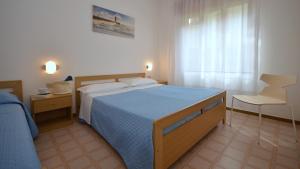 a bedroom with a large bed with a blue blanket at Villa Rosanna in Lignano Sabbiadoro