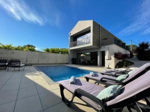 ein Pool mit Chaiselongue und ein Haus in der Unterkunft Casa das Branquinhas - Férias no Minho com piscina! in Ponte de Lima