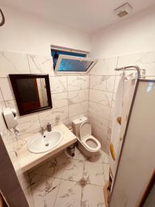 a bathroom with a sink and a toilet and a mirror at KRIS Guesthouse in Berat