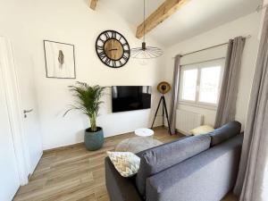 sala de estar con sofá azul y reloj en la pared en Duplex Centre Ville - 50m de la Plage - Clim - Garage - Netflix, en Le Grau-du-Roi