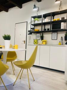 cocina con sillas amarillas, mesa y armarios en Bike&The City, en Ferrara
