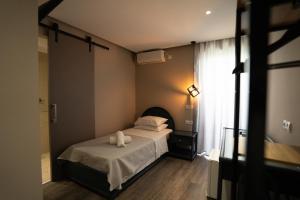 a bedroom with a bed with white sheets and a window at Parthenis Riviera Hotel in Athens