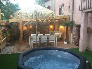 a hot tub in a yard with a table and chairs at La Bohème. Maison de village cosy, jardin et spa. in Octon