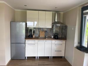 a kitchen with white cabinets and a stainless steel refrigerator at Wrota Biebrzy in Wroceń