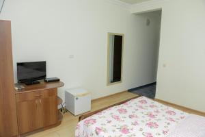a bedroom with a bed and a flat screen tv at Guest House Kvariati in Kvariati