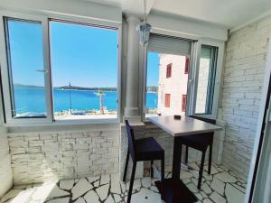 a room with a table and chairs and a view of the ocean at Apartman Cezar2 in Rogoznica