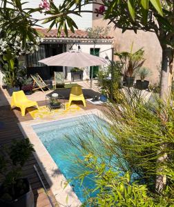 - une piscine avec des chaises jaunes et un parasol dans l'établissement Cosy Studio en Provence, à Carpentras