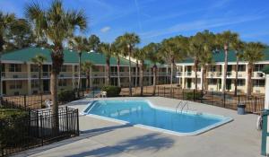 a swimming pool in front of a building with palm trees at Windsor Inn of Jacksonville in Jacksonville