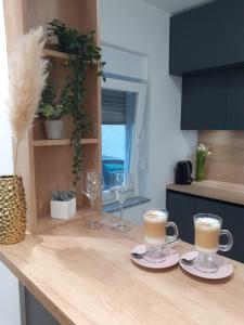 a kitchen counter with two cups of coffee and wine glasses at Apartman Gold in Požega